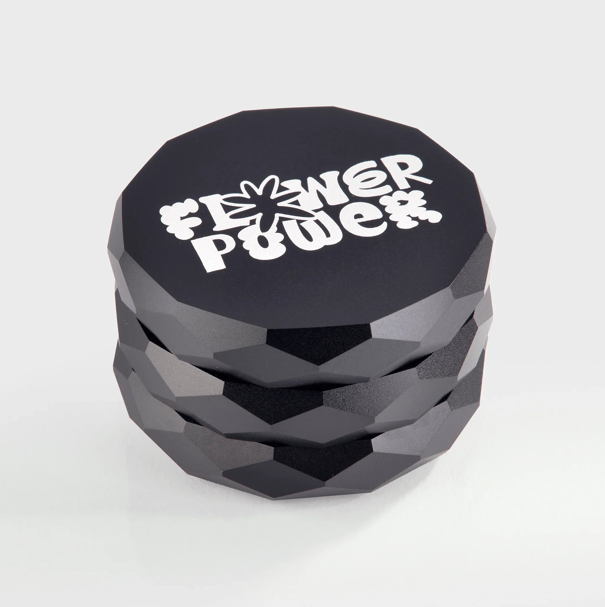Schwarzer Grinder mit Flower Power Logo, facettenreicher Design, ideal für natürliche Produkte