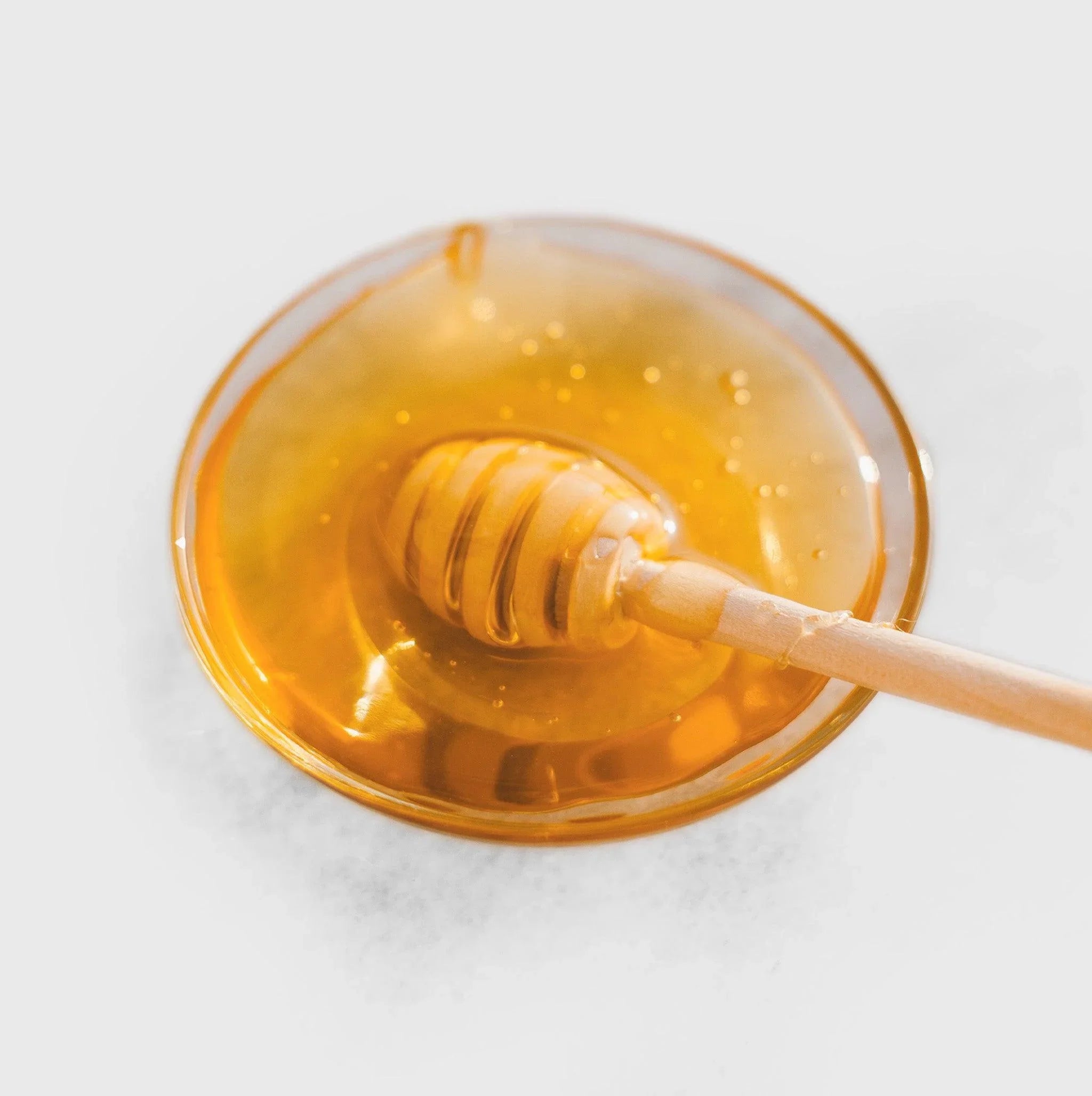 Goldener Honig in Schale mit Holzlöffel, natürlich und rein